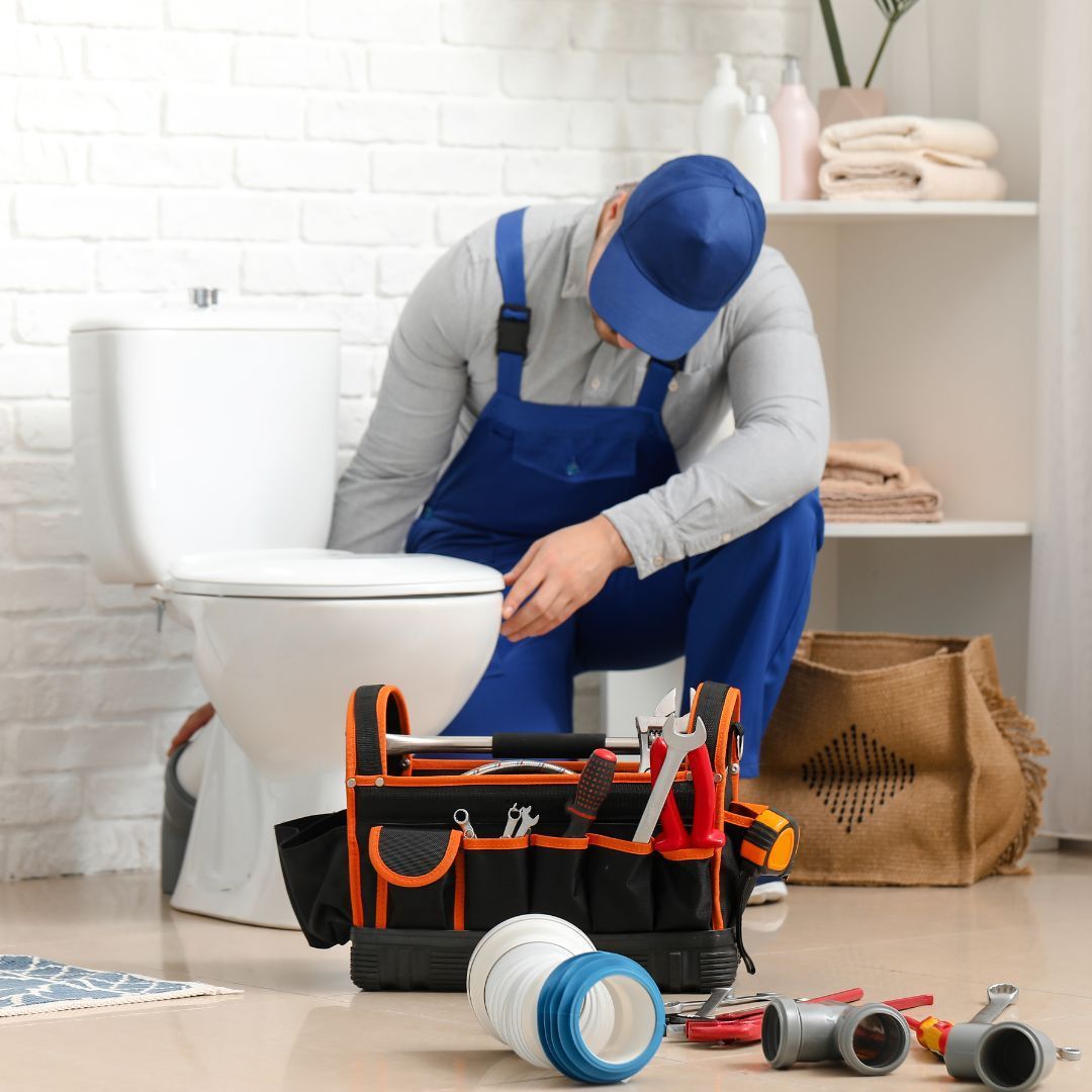 Plumber performing residential plumbing repair in bathroom